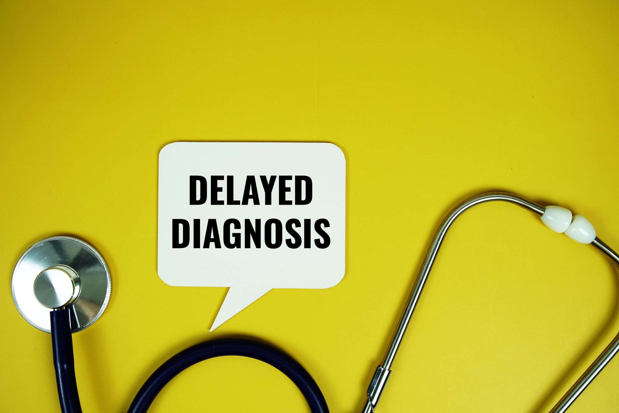 Delayed Diagnosis text with stethoscope on yellow background.
